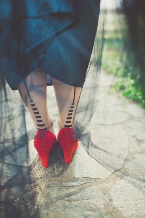 red shoes paired up with stockings with black and white stripes are a fun and cool idea, rock a midi dress to show them off