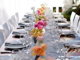 a fresh and cute spring wedding tablescape with white porcelain, white napkins, a white table runner, bold blooms in vases is a lovely idea