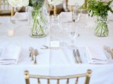 a fresh spring wedding tablescape with white linens, white blooms and greenerycandles and white napkins is amazing