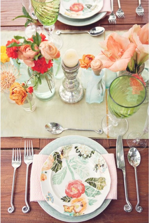 a bright spring wedding tablescape with a light green runner, bold blooms and greenery and printed plates plus peachy napkins