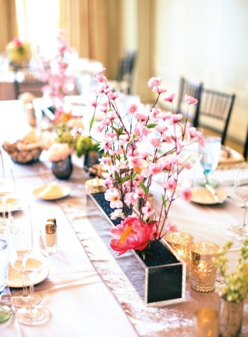 a fantastic spring wedding tablescape with blooming branches in a box as a centerpiece, neutral porcelain and mercury glass candleholders