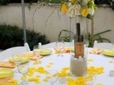 a bright and catchy spring wedding tablescape with yellow and white blooms, yellow petals on the table, yellow plates and orange napkins