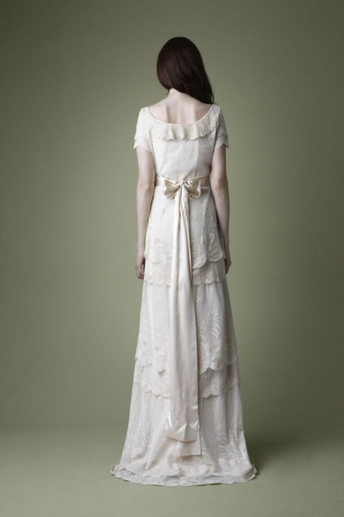 a vintage-inspired wedding dress with ruffles, scallop edge and lace, with short sleeves and a bow wiht long ribbon, a cutout back