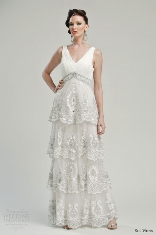 an A-line wedding dress with ruffles, embellishments, a deep V-neckline and no sleeves, an embellished waist for a vintage look