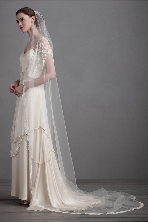 A beautiful vintage champagne colored A line wedding dress with spaghetti straps, a tiered skirt with an embellished rim, a long veil and a train