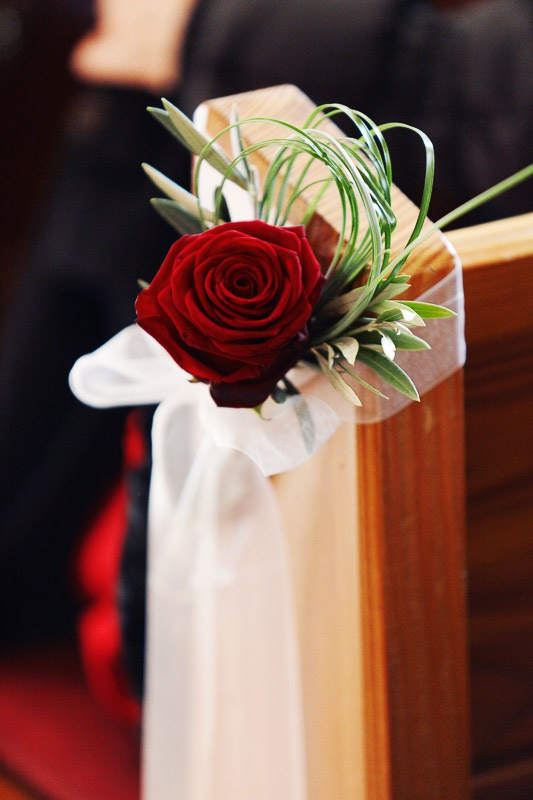 a red rose, greenery and a white ribbon bow are pure elegance to make your winter wedding aisle wow