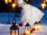 red petals and candle lanterns that line up a winter wedding aisle give it a cozy and chic feel