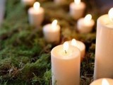 a moss runner with pillar candles is a cool wedding aisle decoration to go for