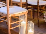 elegant pillar candles in candleholders and neutral blooms highlight the wedding aisle and make it elegant and chic
