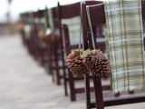 pinecones with green ribbons and green plaid chair covers are cozy and comfy for accenting a winter wedding aisle