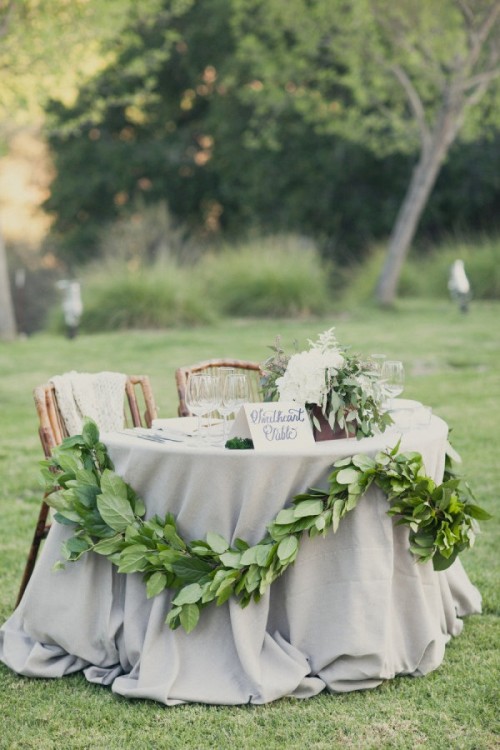 decorate your sweetheart table with a greenery garland to mark it subtly and in a fresh and chic way