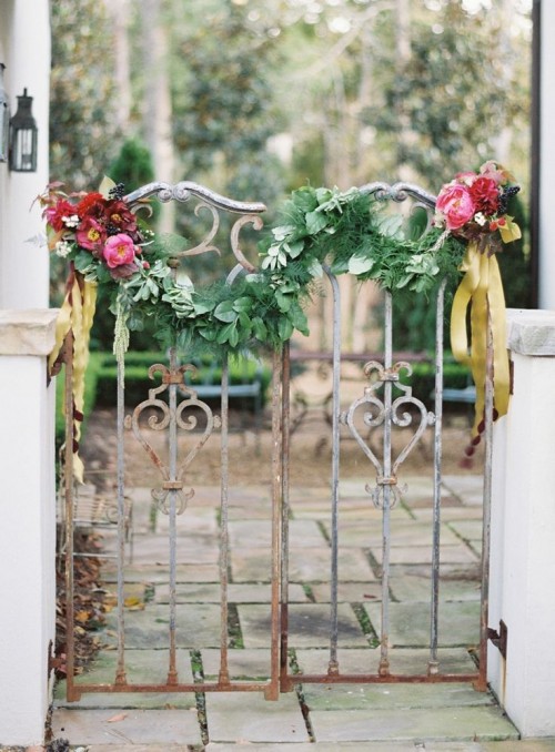 a gate decorated with greenery and blooms can be even used as a simple and cute wedding backdrop