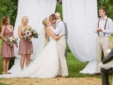 a curtain wedding backdrop with a lush greenery garland over it is a simple wedding backdrop idea