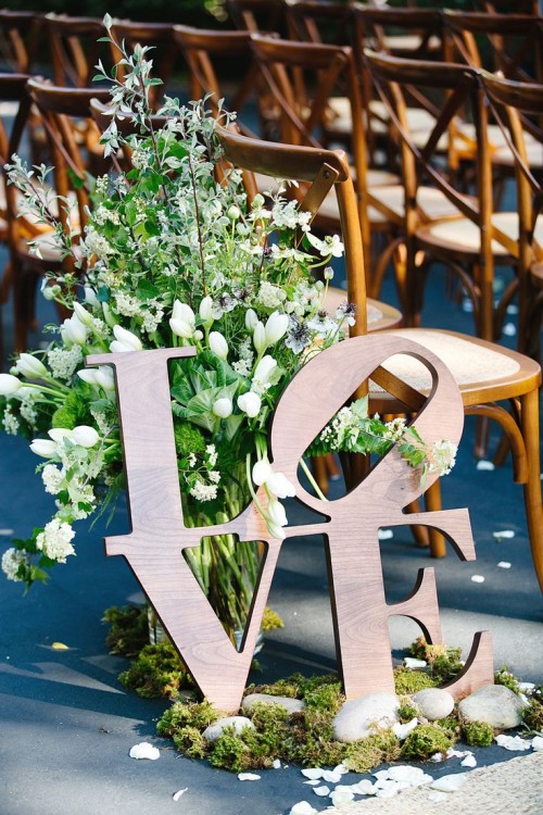 a greenery and white bloom decoration, with moss and pebbles plus LOVE letters is a creative wedding aisle decoration