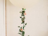 a large white balloon with greneery and peachy blooms is a cool wedding decoration