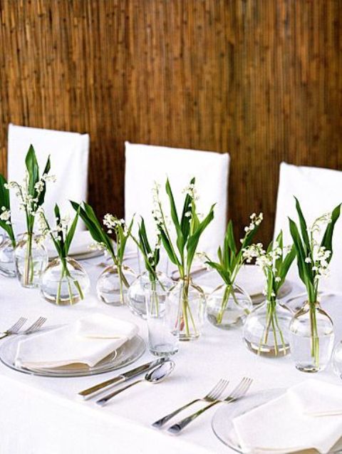 greenery and lily of the valley in clear glass bottles make the table look airy and ethereal
