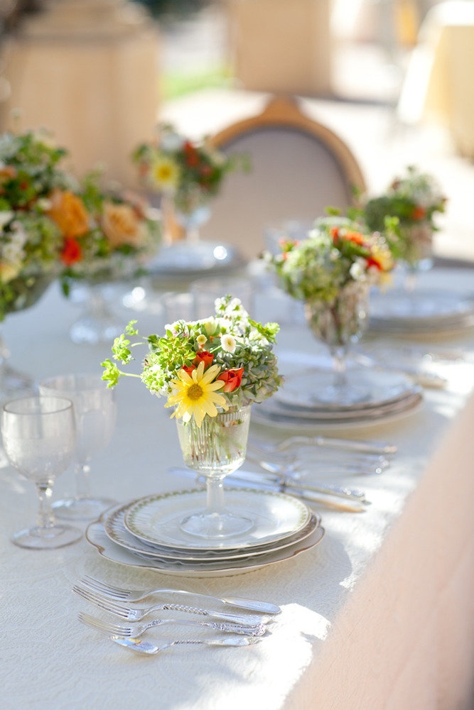 glasses with greenery and bright blooms will spruce up your wedding place settings in a cool way