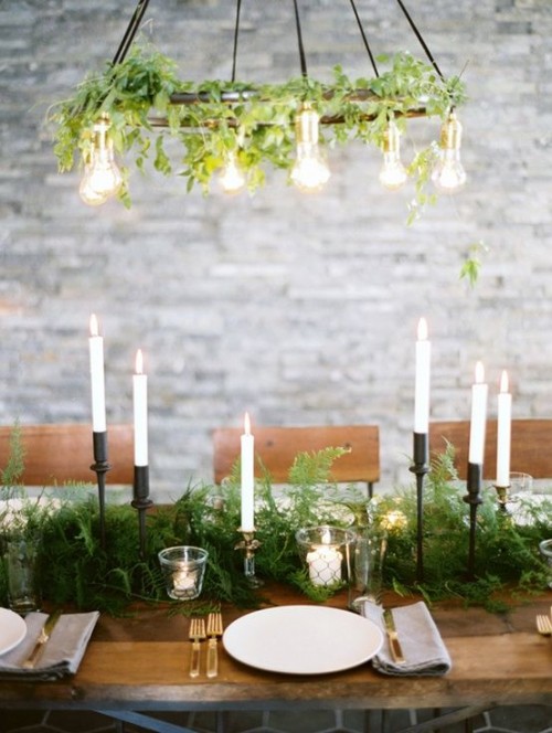 a fern table runner and a greenery chandelier with bulbs is a cool combo for a wedding tablescape