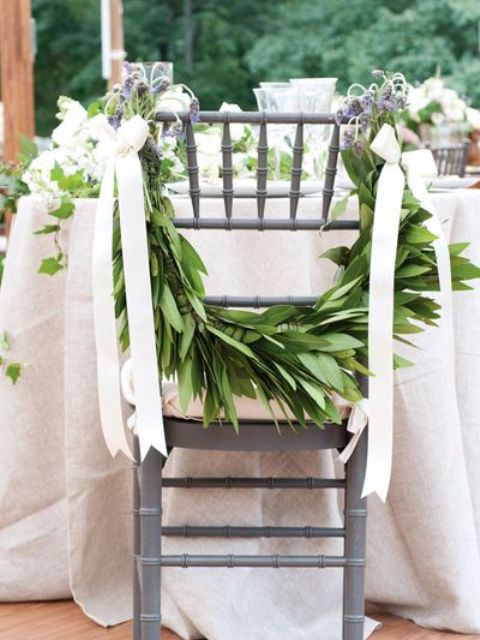 spruce up wedding chairs with lush greenery and white bows instead of usual signage or wreaths