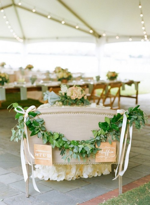 a sweetheart loveseat decorated with greenery and white ribbons is a cool idea to highlight your couple's seating