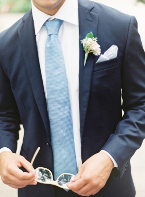 a navy suit, a white shirt, a light blue tie and a neutral boutonniere for a simple, elegant groom's look