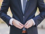a navy suit, a white shirt are spruced up with a navy and white striped tie and a catchy boutonniere