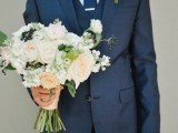 a navy three-piece suit, a white shirt and a navy tie plus a boutonniere for a bold and stylish look