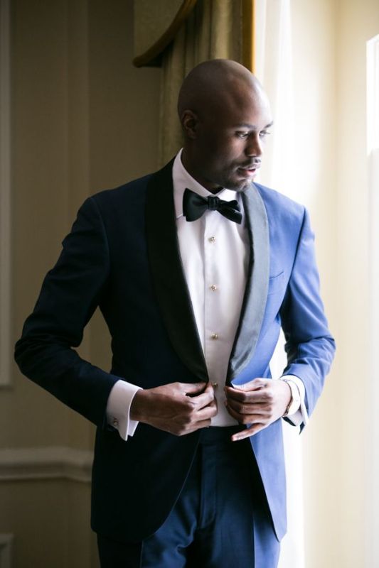 A super elegant navy tuxedo with black lapels, a black bow tie and a white shirt with pearly buttons