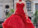 a hot red strapless wedding dress with a lace bodice and a plain skirt, a red lace neck piece and black shoes for a colorful wedding