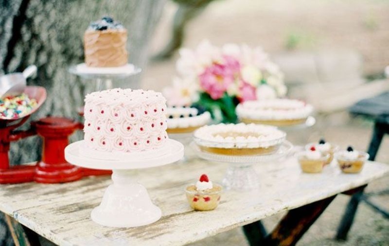 Simple glass and white stands for an assortment of wedding cakes on a shabby chic table