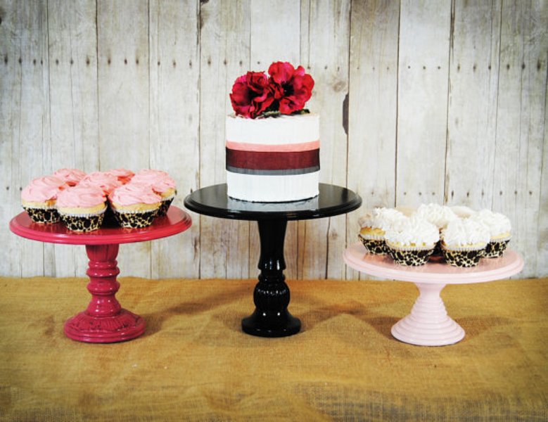 wooden stands of pink for cupcakes and a black cake stand make up a rustic and a cool sweets table