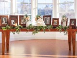 a sweets wedding table with greenery and family photos of people who are gone but loved and white wedding cakes