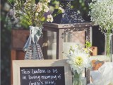 a rustic wedding table with blooms, candles and a sign that is telling about lighting the lantern in memory of a person who is gone