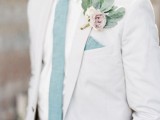 a delicate spring groom’s look with a white suit, a white shirt, a mint tie and a handkerchief, a delicate pastel floral boutonniere