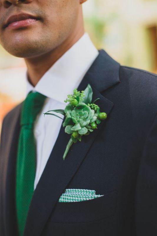 A catchy groom's look with a black suit, a white shirt, an emerald tie and a bold emerald handkerchief, plus a greenery and succulent boutonniere