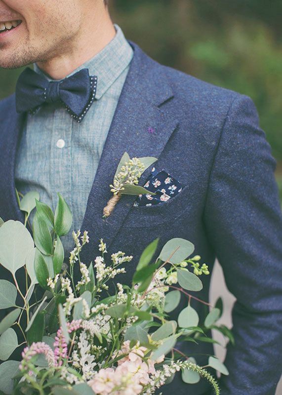 A navy wooled suit, a grey shirt, a navy bow tie and a dark floral handkerchief plus a greenery boutonniere for an ultimate fall groom's look