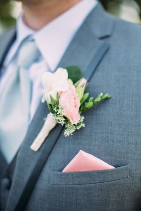 A classic groom's look with a grey suit, a white shirt, a pastel blue tie, a pink floral boutonniere and a pink handkerchief never goes out of style