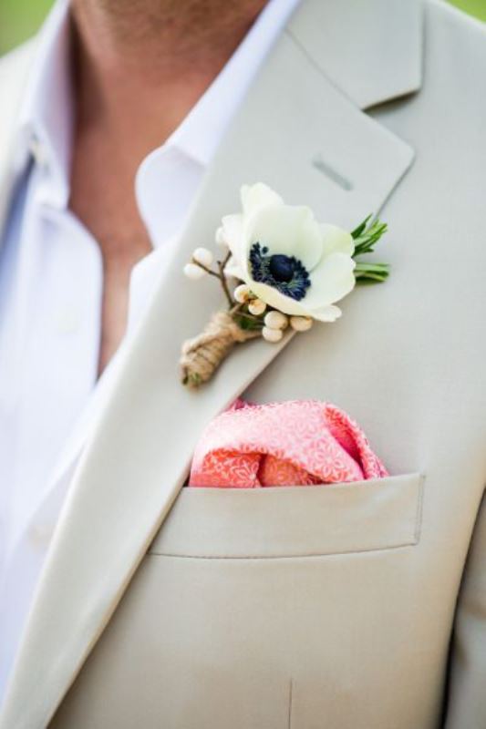 A summer groom's look with a creamy suit, a white shirt, a white anemone boutonniere and a pink handkerchief is perfect for hot locations and tropical weddings