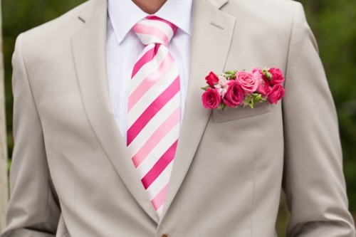 a pretty neutral groom's look with a tan suit, a white shirt, a bold pink striped tie and a bold pink floral pocket square is cool for a summer wedding