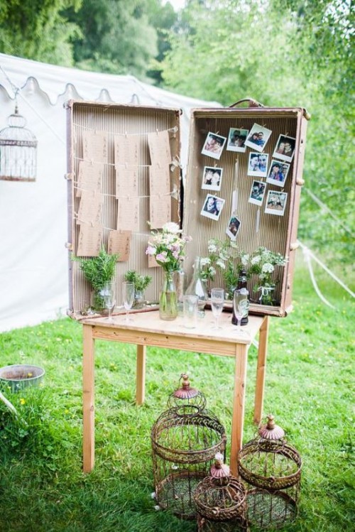 a large vintage suitcase with wildflowers, couple's photos and a wedding seating plan is a cool solution for a vintage wedding