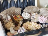 a large navy wedding suitcase decorated with polka dots and a letter banner, some sweets and candies, pockets and tags is a great alternative to a usual dessert table