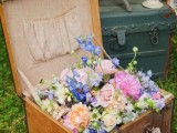 a vintage suitcase filled with blue, pink and white blooms and greenery is a beautiful decoration for a vintage wedding, it can be rocked for a spring or summer celebration