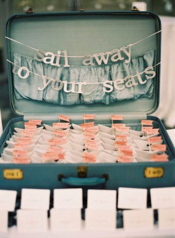 A vintage suitcase with a letter banner and some cards attached to little boats is a cool idea for a seaside or beach wedding