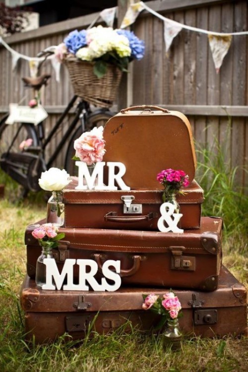 a stack of vintage suitcases decorated with white, pink and fuchsia blooms and with letters is a lovely vintage wedding decoration to try