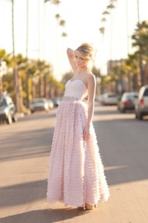a strapless blush wedding dress with a draped bodice and a ruffle midi skirt and an embllished sash