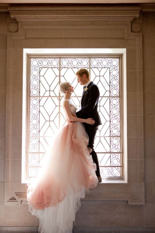 an ombre pink and white wedding ballgown with a strapless bodice and a layered skirt with a train