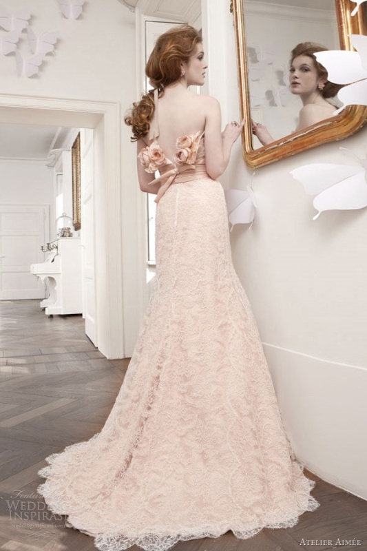 a beautiful blush lace A line wedding dress with blush fabric blooms decorating the open back
