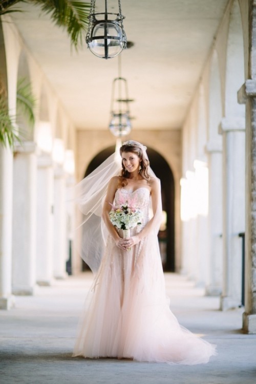 a blush lace A-line wedding dress with a tulle skirt and a lace bodice plus a matching veil for a modern romantic bridal look