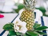 a pineapple with leaves and neutral blooms form a great and simple wedding centerpiece for a tropical wedding