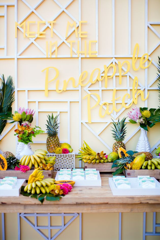 A fruit table with lots of bananas, papayas, pineapples, leaves and bright blooms is great instead of a usual dessert table